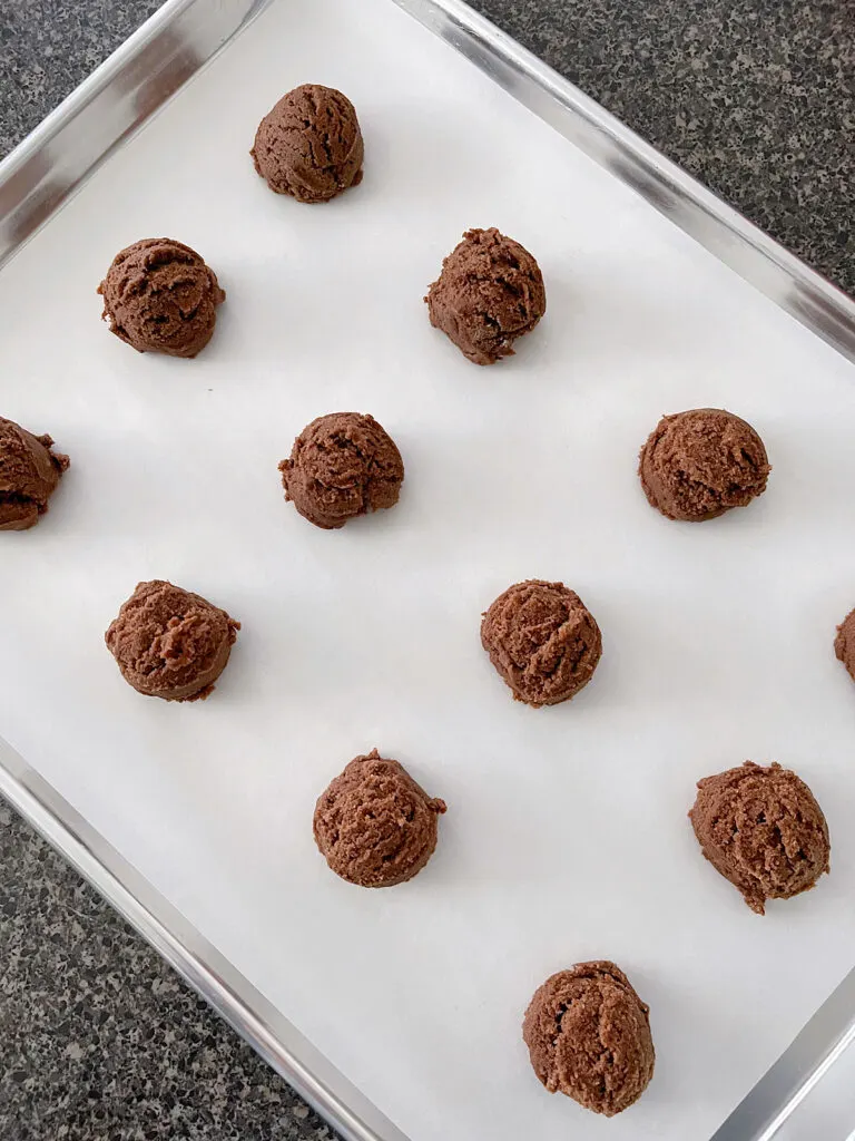 Hot chocolate cookie dough balls on a baking sheet.