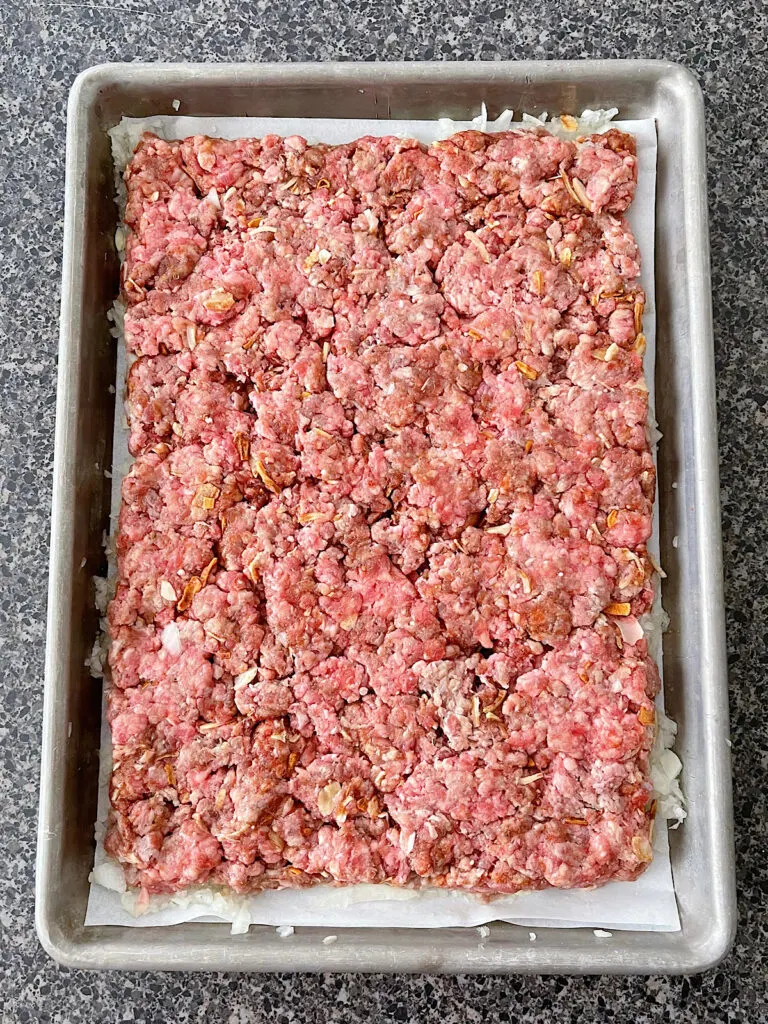 A large hamburger patty on a parchment paper lined baking sheet.