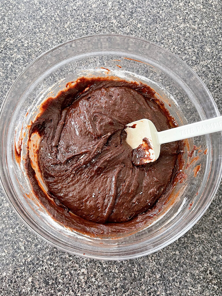 Brownie batter in a mixing bowl with a silicone spatula.