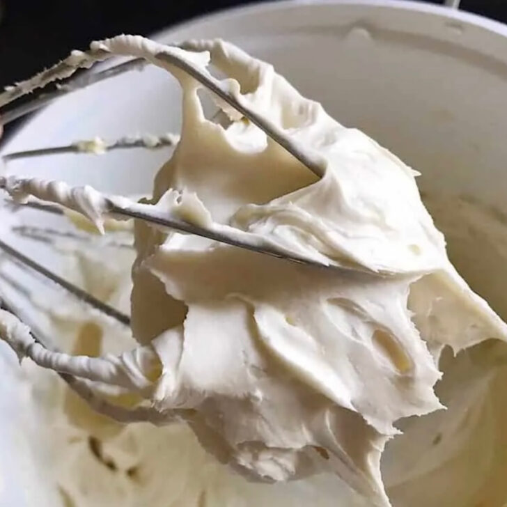 Cream cheese frosting on a whisk attachment for a stand mixer.