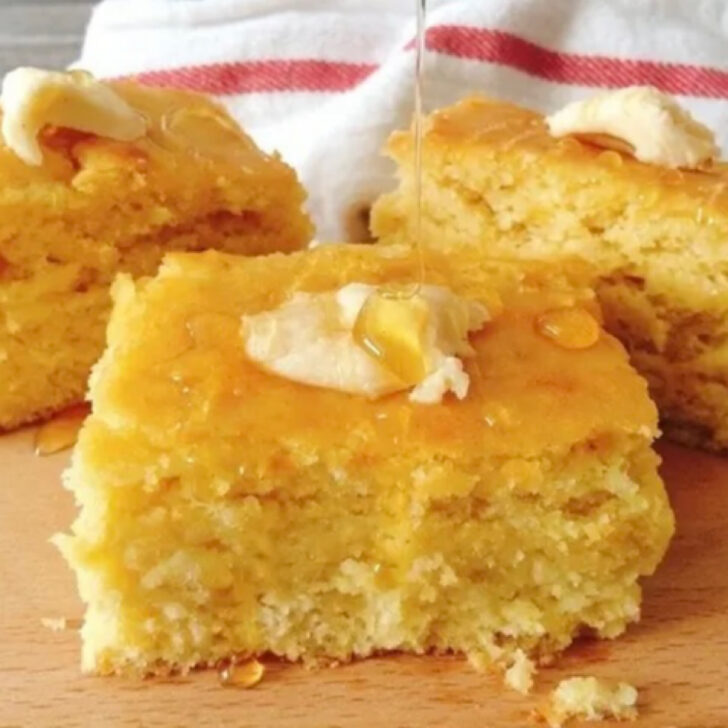 Sweet moist cornbread cut into squares and topped with butter and honey.