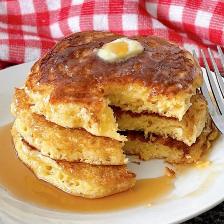 A plate of sour cream pancakes with butter and syrup.