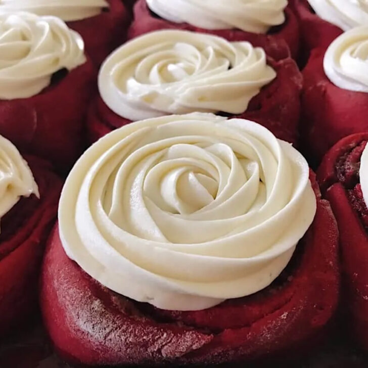 A pan of red velvet cinnamon rolls with cream cheese frosting.