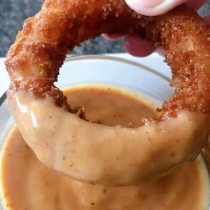 An onion ring dipped in copycat Red Robin Onion Ring Sauce.