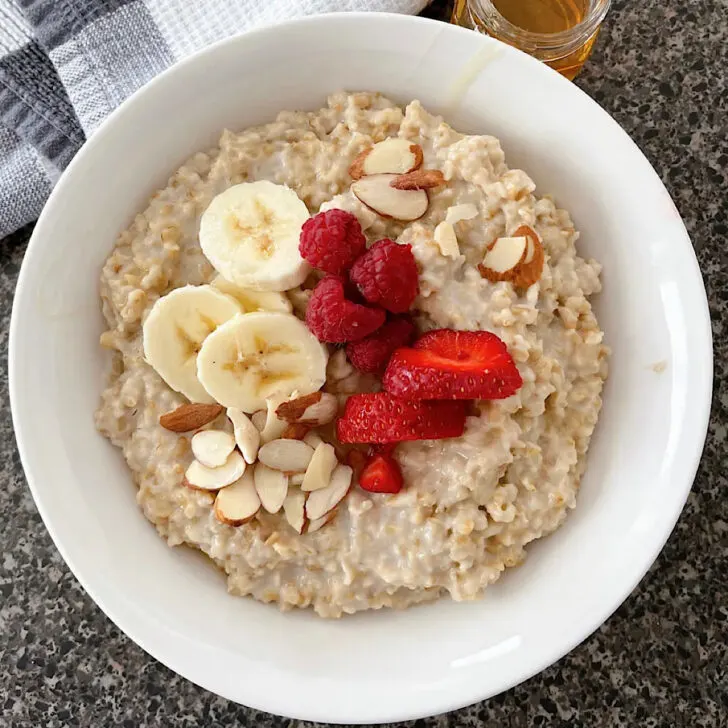 A bowl of steel cut oatmeal topped with bananas and strawberries.