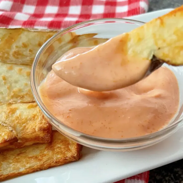 A potato wedge dipped in fry dipping sauce.