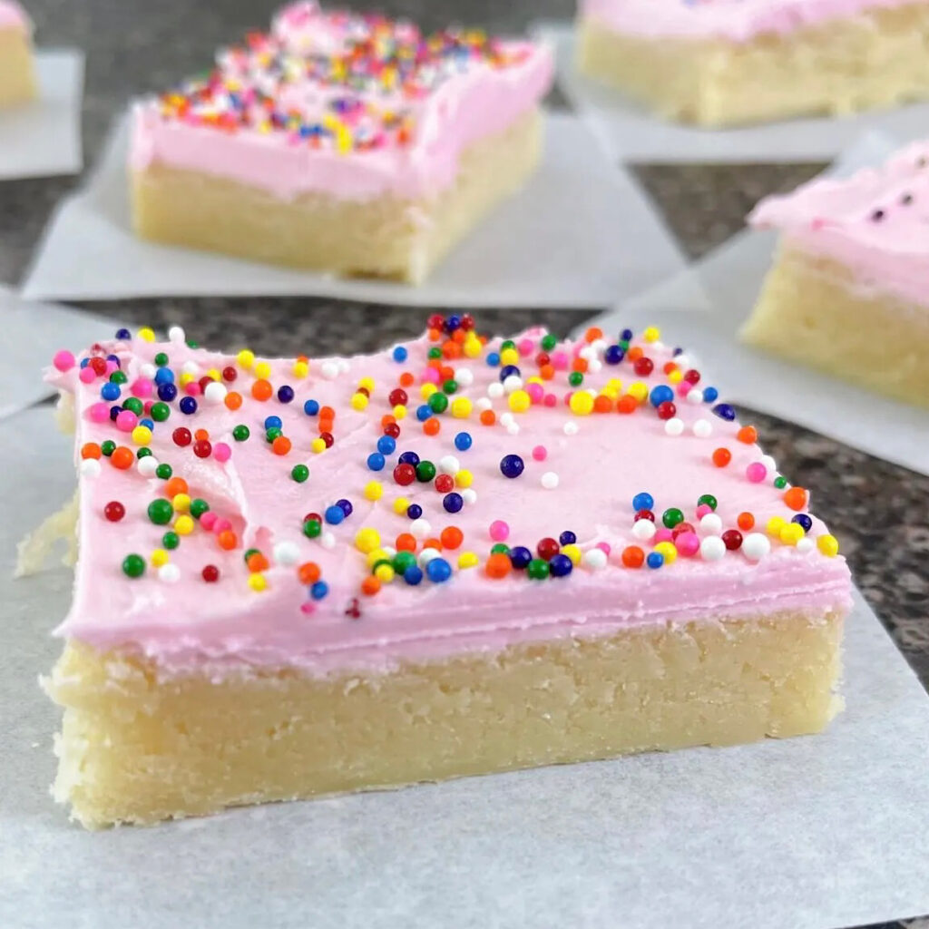 Cream cheese sugar cookei bars with pink frosting and sprinkles.