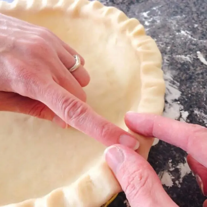 Two hands forming homemade butter pie crust.