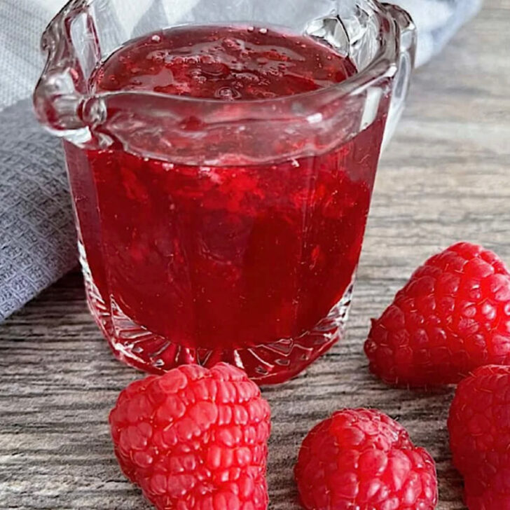 A container of homemade raspberry syrup.