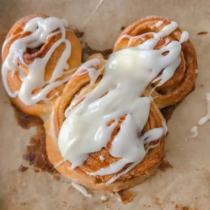 A Mickey Mouse shaped cinnamon roll with icing.