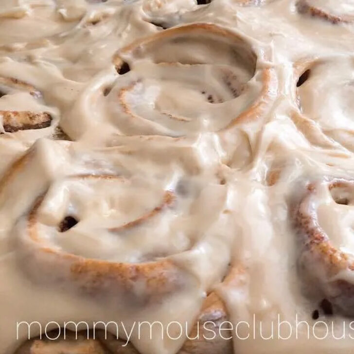 A pan of butter pecan cake mix cinnamon rolls topped with caramel cream cheese icing.