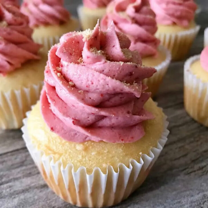 A cheesecake cupcake topped with strawberry frosting.