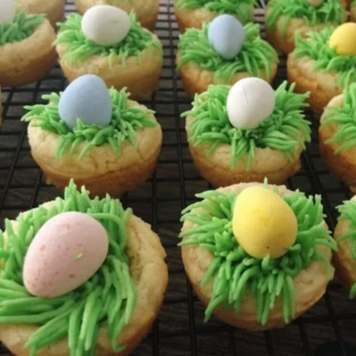 Sugar cookie cups filled with green frosting and candy easter eggs.