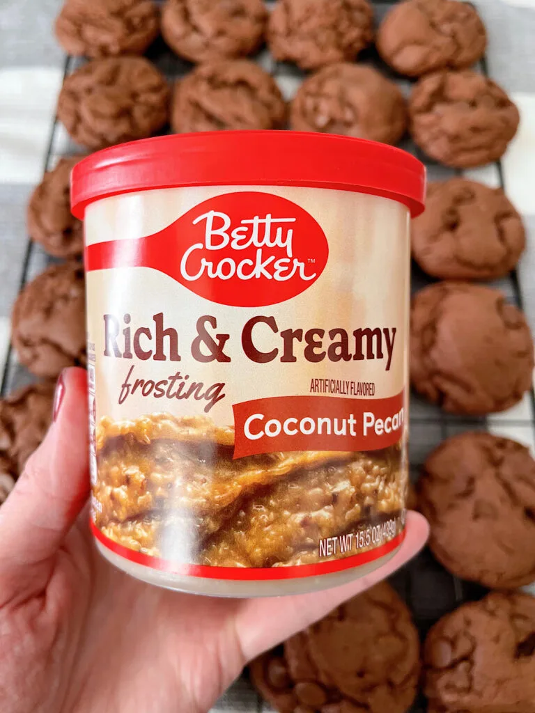 A container of coconut pecan frosting over chocolate cookies.