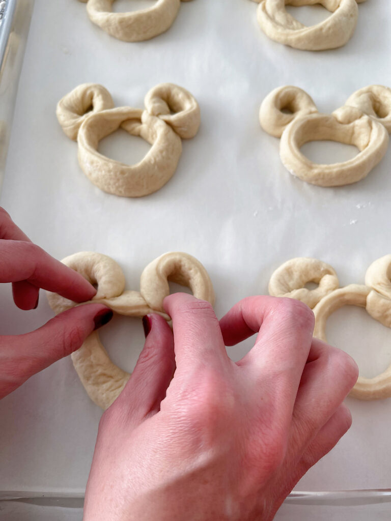 Two hands forming a Mickey Mouse pretzel.