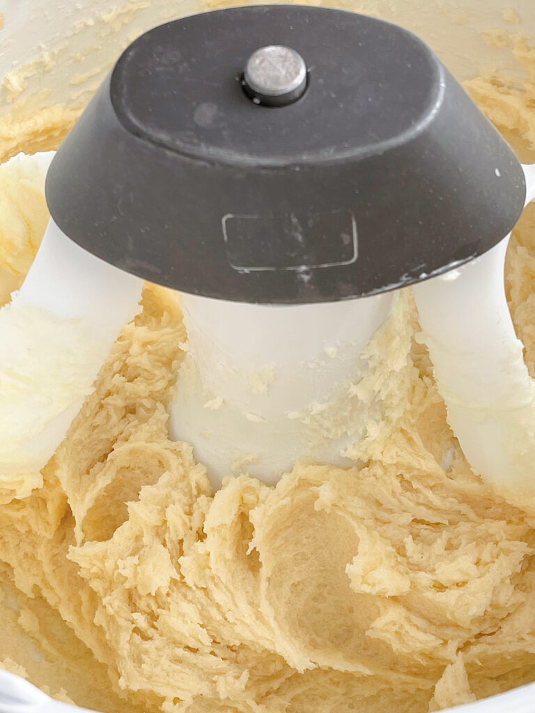 Sugar cookie dough in the bowl of a stand mixer.