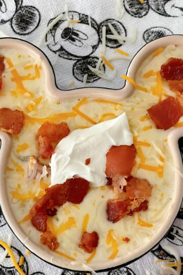 Disneyland's Loaded Baked Potato Soup in a Mickey Mouse-shaped bowl with sour cream and bacon.