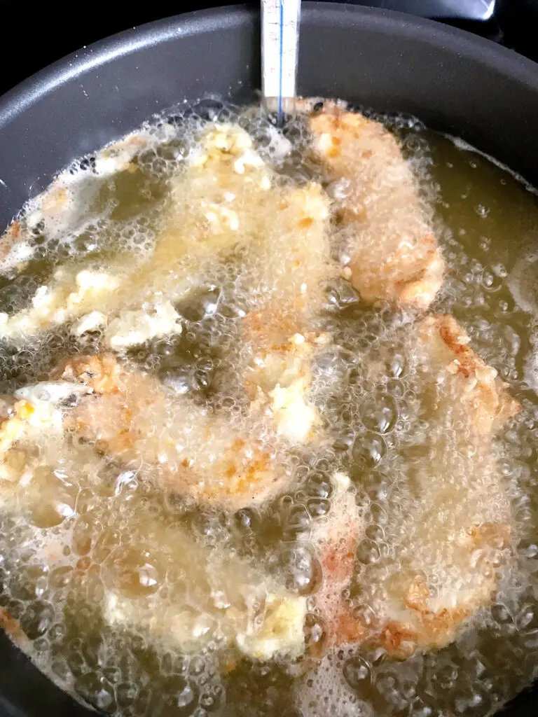 Sage fried chicken frying in oil.
