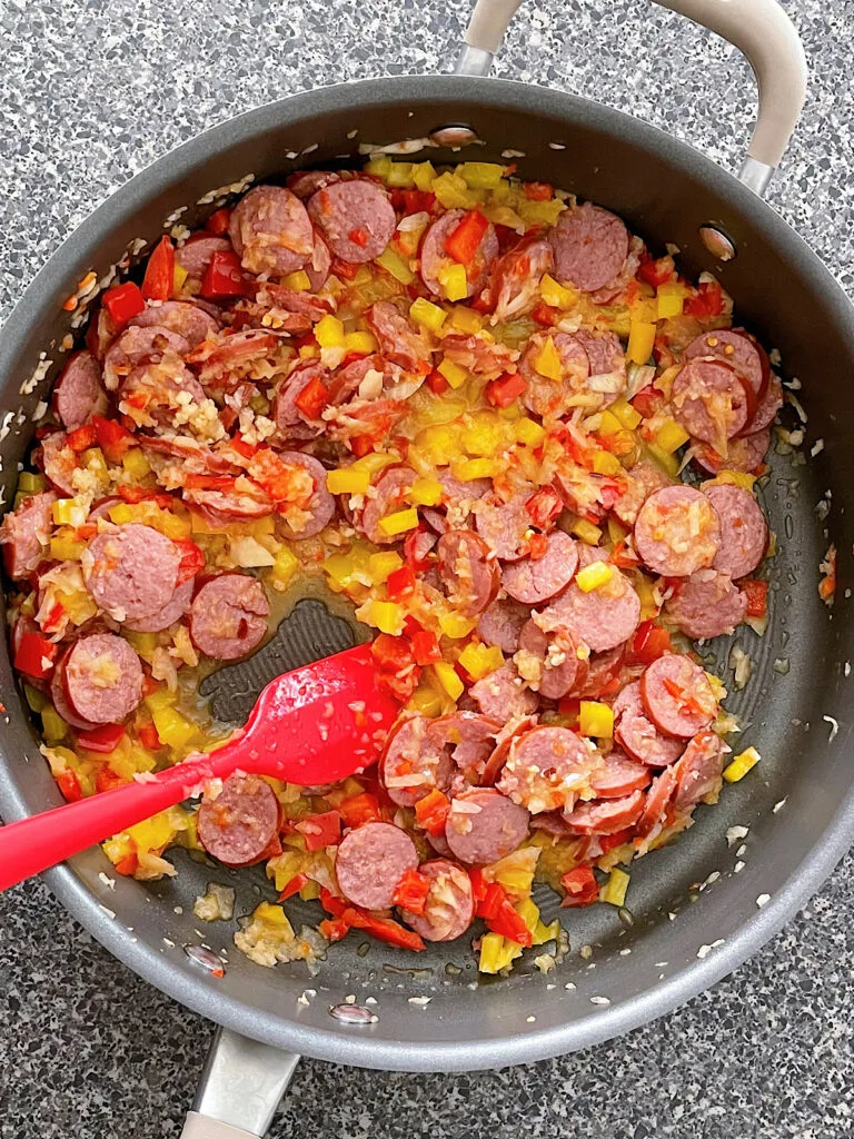Sausage, onions, peppers, garlic, and red pepper flakes in a sauce pan.