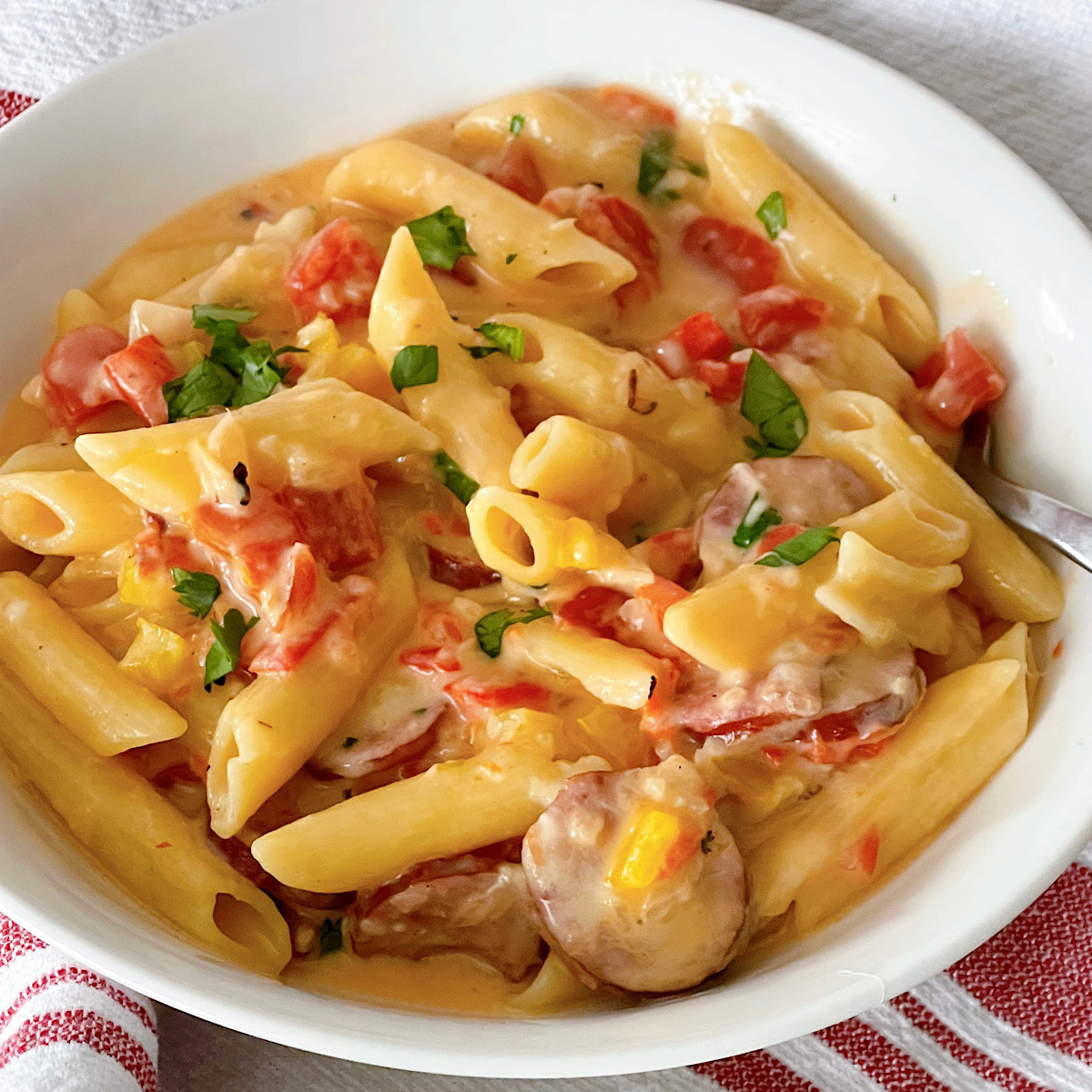 Spicy sausage pasta in a bowl with a fork.