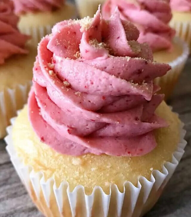 A strawberry cheesecake cupcake with strawberry buttercream and graham cracker crumbs.
