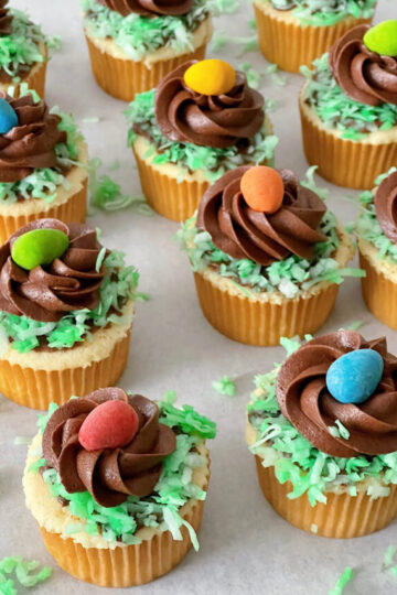 Vanilla cupcakes with green coconut, chocolate frosting and an Easter egg candy.