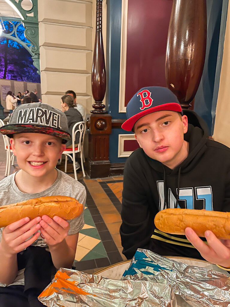 Two kids eating hot dogs from Casey's Corner at Disneyland Paris.