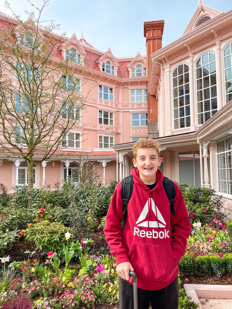 A teenager standing in front of the Disneyland Hotel Paris.