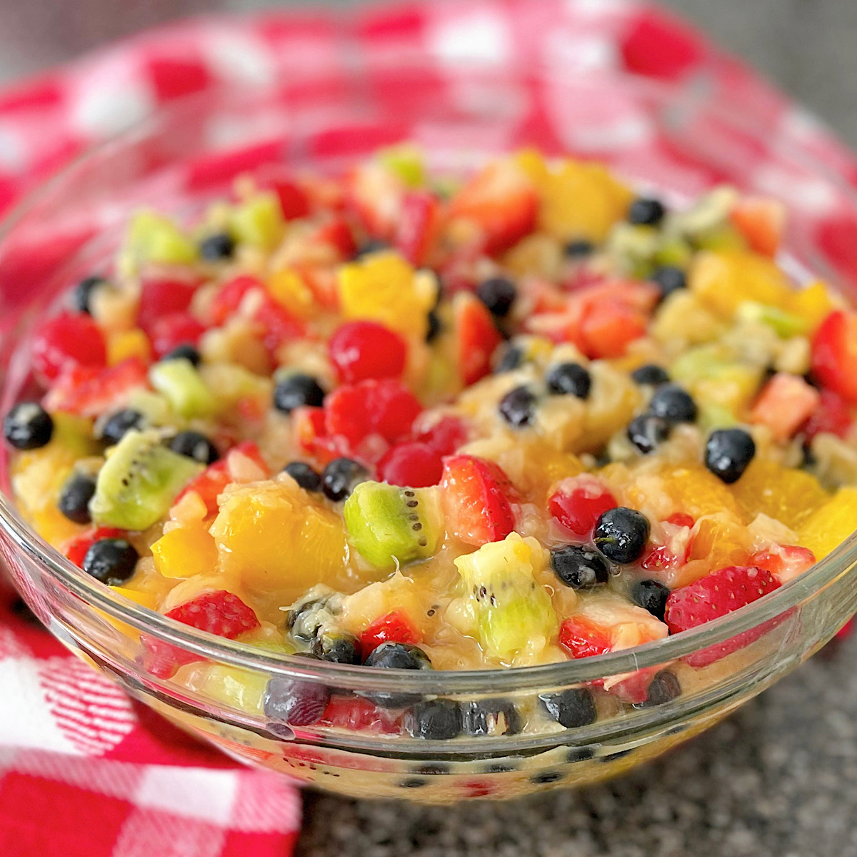 Vanilla pudding glazed fruit salad in a glass bowl.