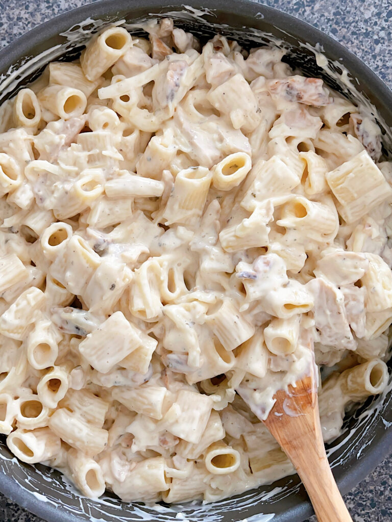 Garlic Parmesan Chicken Alfredo and pasta mixed in a pan.
