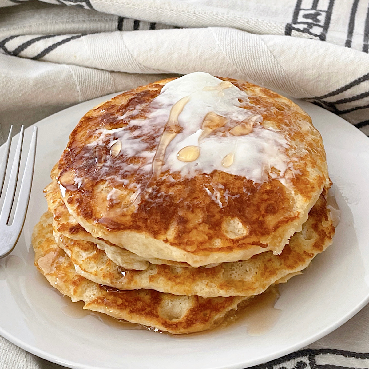 A stack of copycat IHOP Pancakes with butter and syrup.
