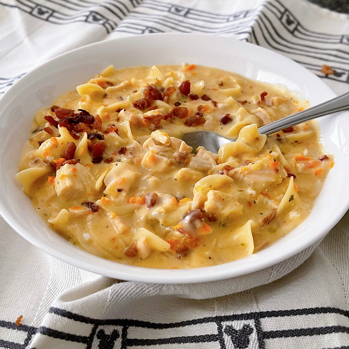 A bowl of crack chicken noodle soup with bacon, ranch, and cheese.