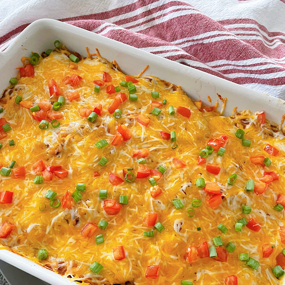 Mexican pizza casserole topped with shredded cheese and tomatoes.