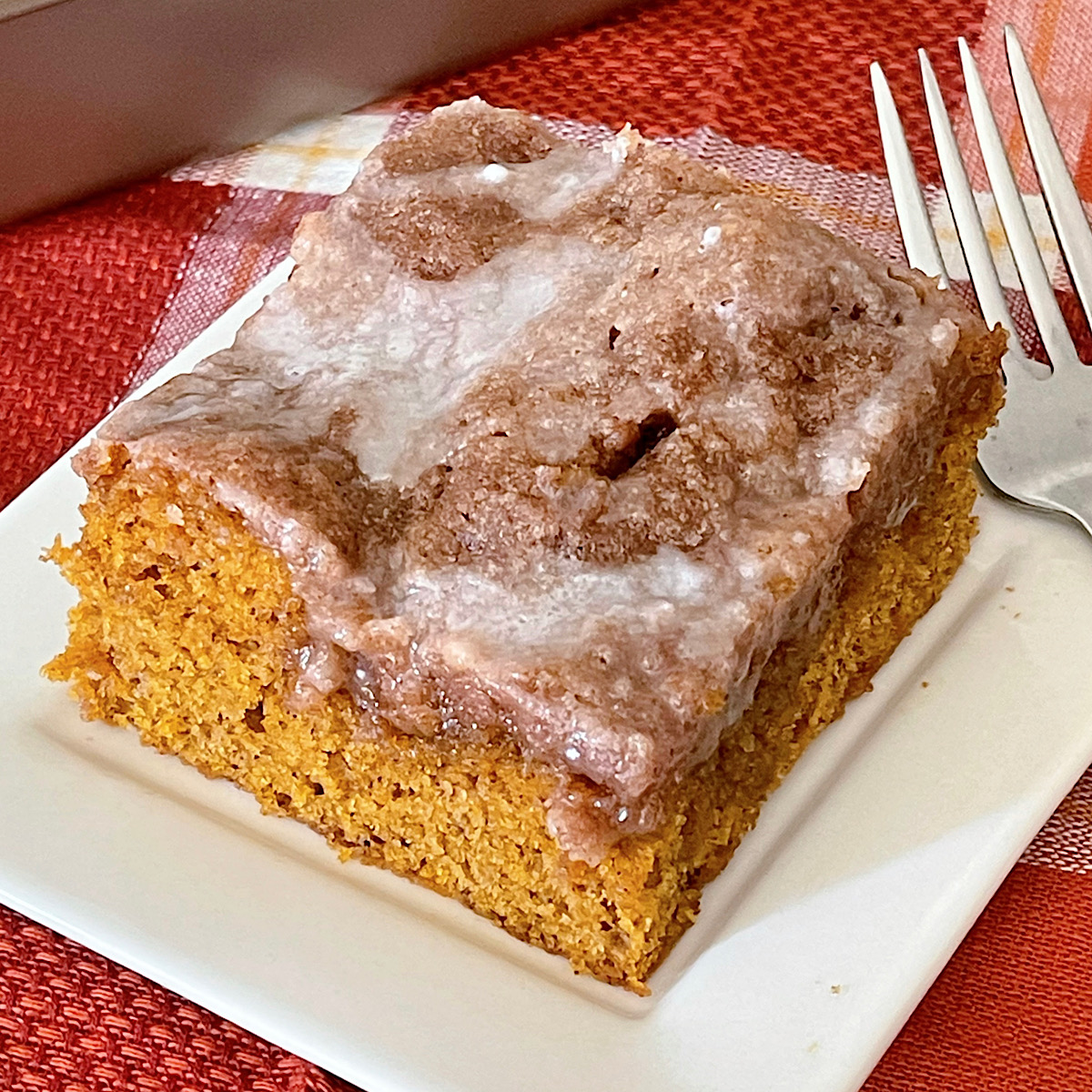 A slice of pumpkin spice crumb cake on a white place with a fork.