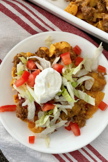 A serving of Walking Taco Casserole topped with lettuce, tomato, and sour cream.