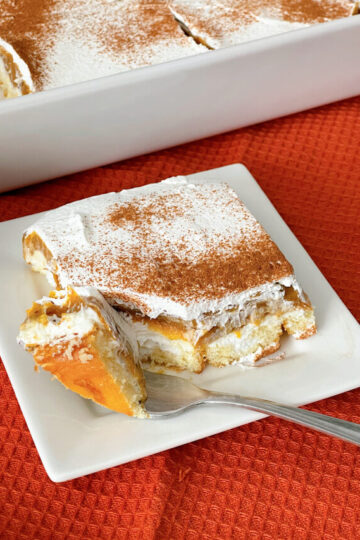 A slice of Twinkie Pumpkin Delight with layers of Twinkies, no bake cheesecake, pumpkin pie, and whipped cream.