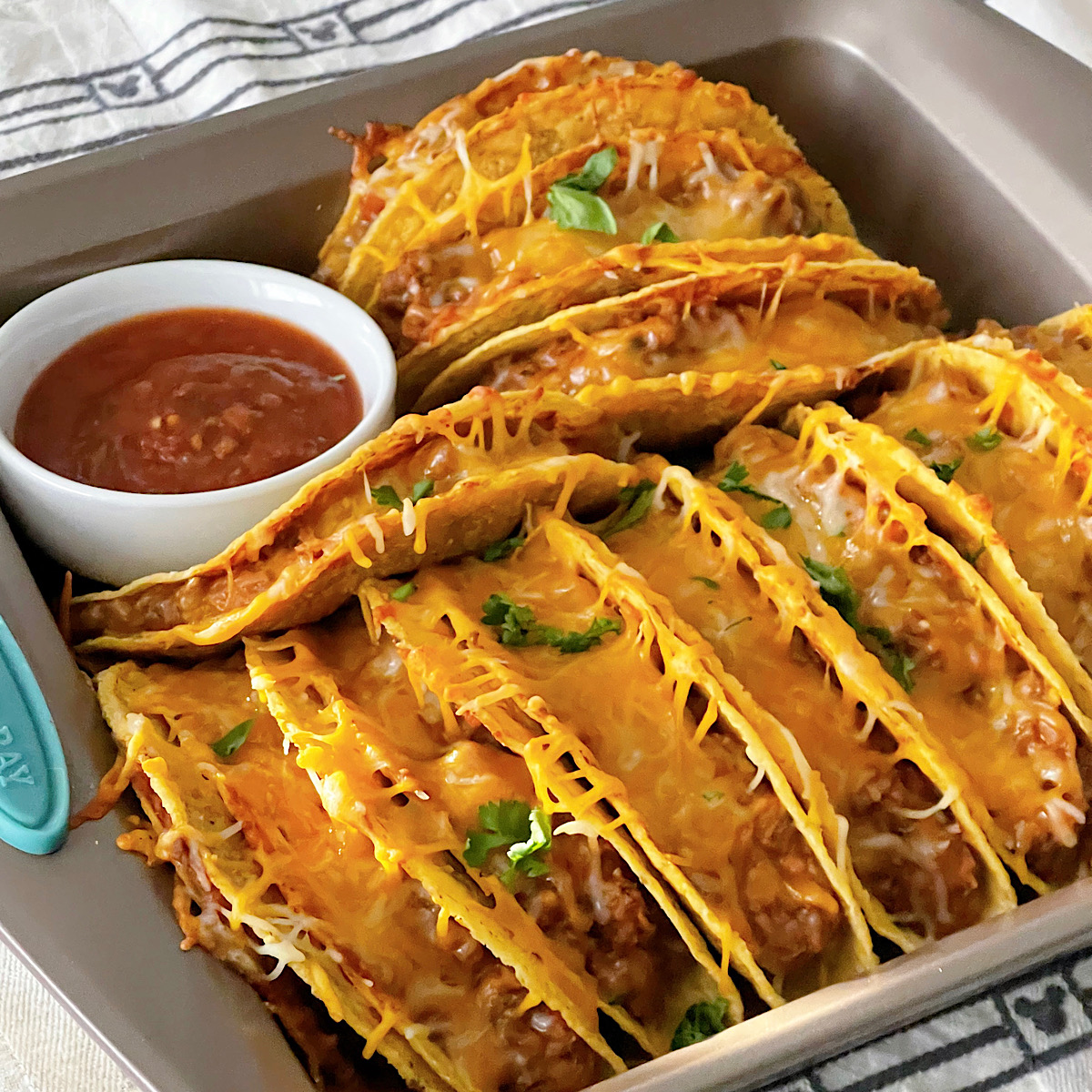 Oven baked tacos in a white baking dish.