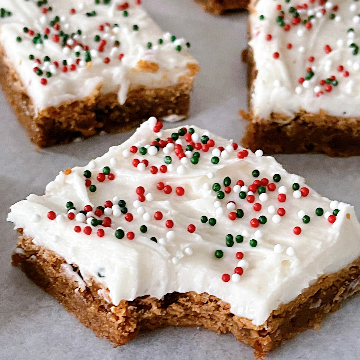 A gingerbread cookie bar topped with buttercream and Christmas sprinkles.