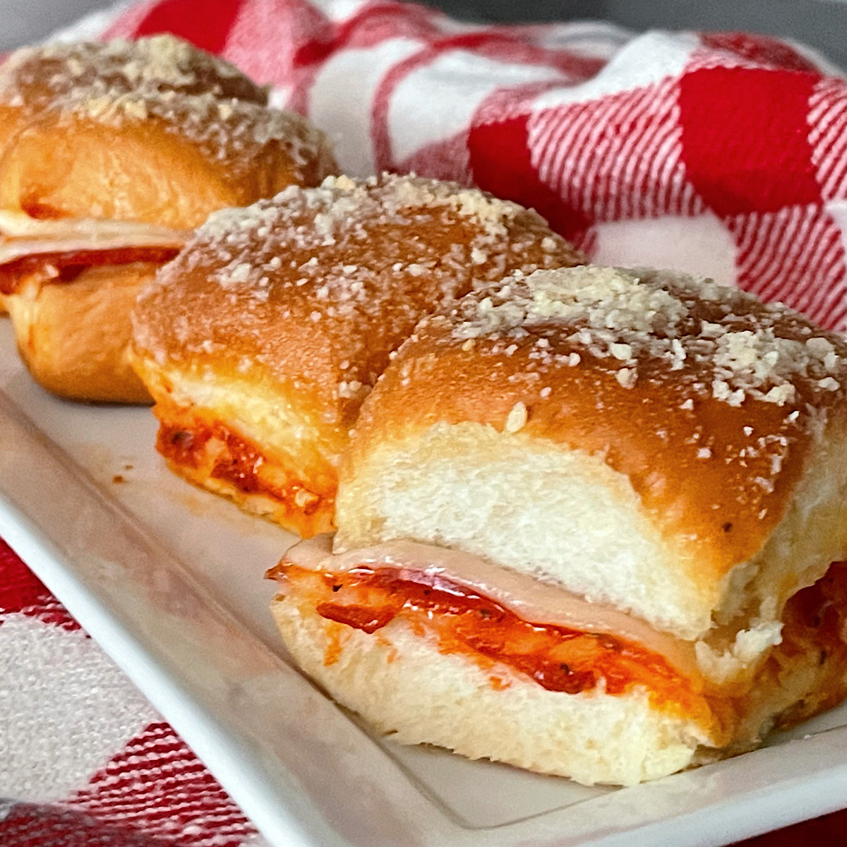 Four pizza sliders on a white plate.