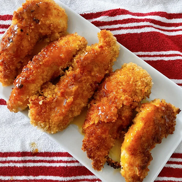 Hot honey chicken tenders on a white plate.