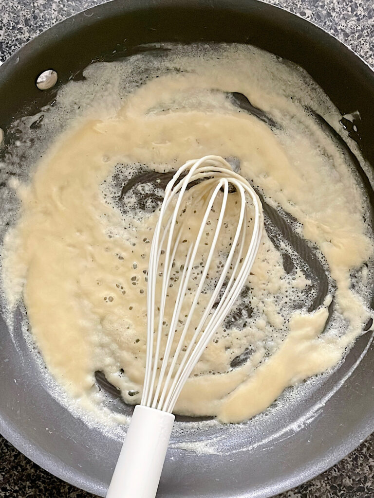 Flour and melted butter in a saucepan with a white whisk.