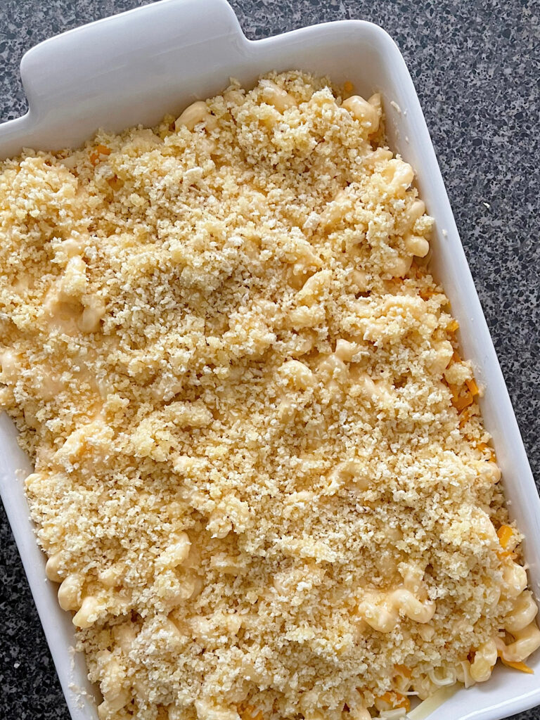 Homemade macaroni and cheese in a white baking dish topped with breadcrumbs.