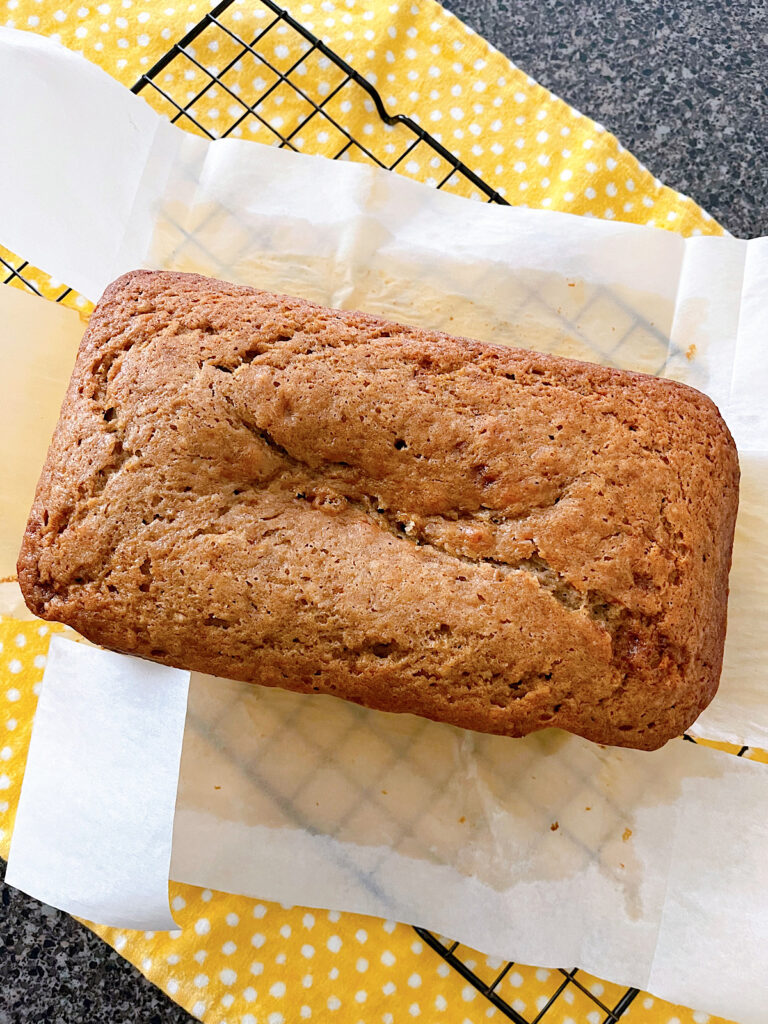 A loaf of banana bread on a cooling rack.