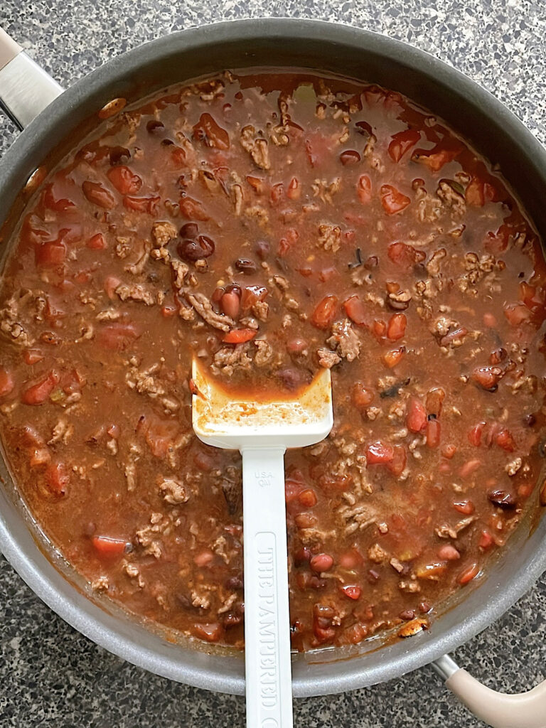 Beans, Rotel, ground beef, and enchilada sauce in a saucepan.