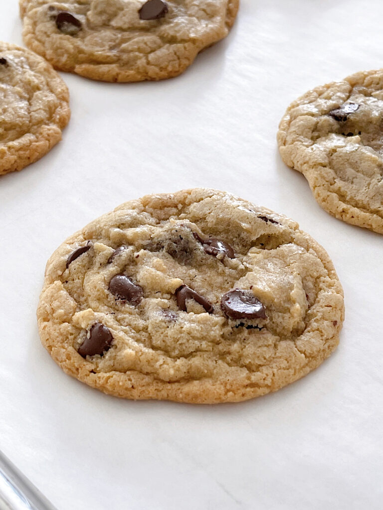 A freshly baked sourdough chocolate chip cookie on parchment paper.