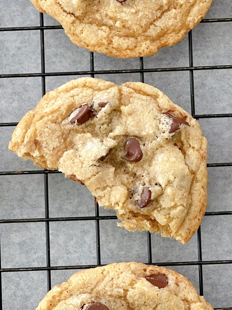 Half of a chocolate chip cookie on a cooling rack.