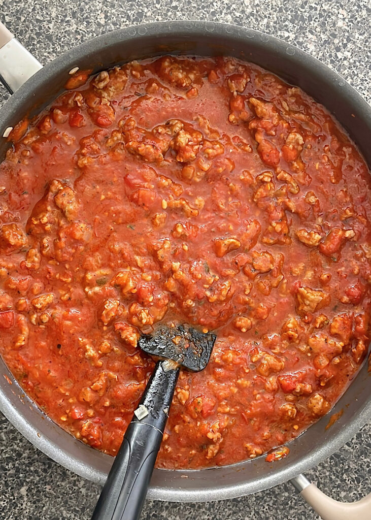 A pan of marinara sauce with Italian sausage.
