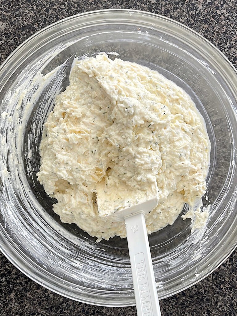 Cream cheese, ricotta cheese, an egg, and spices mixed together in a bowl.