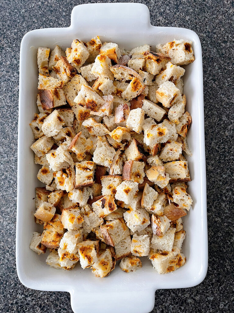 Cubed sourdough bread in a white baking dish.