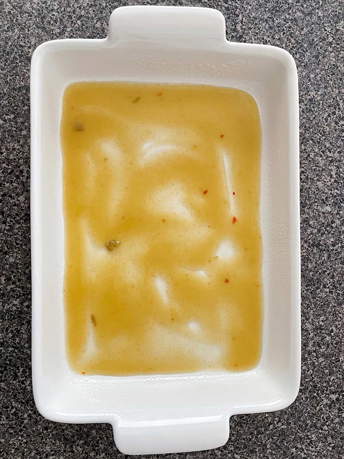 Green enchilada sauce spread in a baking sheet.